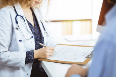 Kadın doktor ve erkek hasta güneşli klinikte otururken sağlık muayenesini tartışıyorlar. Yakın plan. İlaç, sağlık hizmetleri