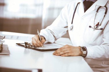 Bilinmeyen erkek doktor, klinikteki ilaç geçmişi kayıtlarıyla birlikte yakın planda oturuyor. İşteki genç doktor. Mükemmel sağlık hizmeti, tıp konsepti