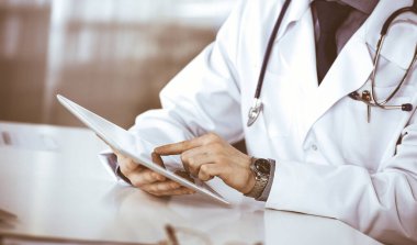 Bilinmeyen erkek doktor klinikteki tablet bilgisayarla yakın planda çalışıyor. İşteki genç doktor. Mükemmel sağlık hizmeti, tıp konsepti