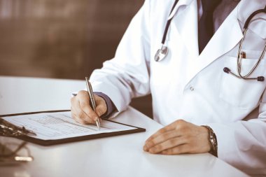 Bilinmeyen erkek doktor, klinikteki ilaç geçmişi kayıtlarıyla birlikte yakın planda oturuyor. İşteki genç doktor. Mükemmel sağlık hizmeti, tıp konsepti