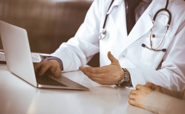 Bilinmeyen erkek doktor ve hasta kadın klinikte oturup dizüstü bilgisayar kullanırken bir şeyler tartışıyorlar. Hastanedeki en iyi sağlık hizmeti, ilaç, salgın durdurma.