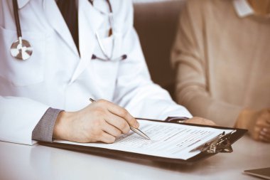 Bilinmeyen erkek doktor ve hasta kadın klinikte oturup dosya kullanırken bir şey tartışıyorlar. Hastanedeki en iyi sağlık hizmeti, ilaç, salgın durdurma.