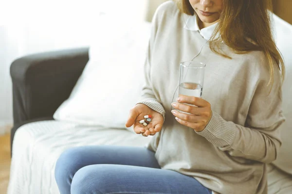 Yakın plan kadın hapları tutuyor, ilaç alıyor, baş ağrısını tedavi ediyor, yüksek tansiyon ilaçları evde. Coronavirus salgını sırasında evde konsept kal