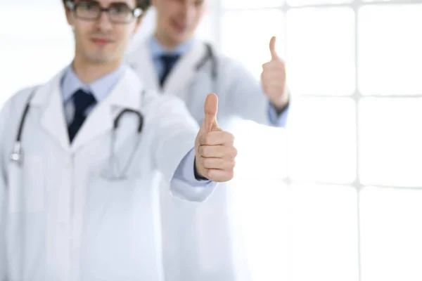 Zwei männliche Ärzte stehen als Team und zeigen Daumen nach oben als Symbol für den besten Service für Patienten in der Klinik. Medizin und Gesundheitsfürsorge — Stockfoto