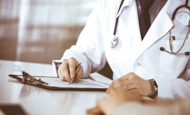 Bilinmeyen erkek doktor ve hasta kadın klinikte oturup dosya kullanırken bir şey tartışıyorlar. Hastanedeki en iyi sağlık hizmeti, ilaç, salgın durdurma.