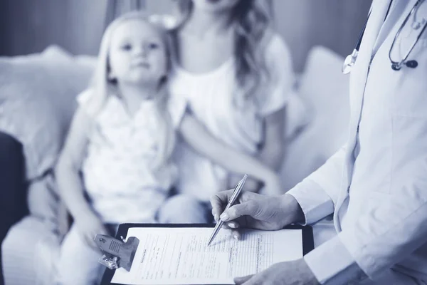 Doctor y paciente. Pediatra usando portapapeles mientras examina a la niña con su madre en casa. Niña enferma e infeliz en el examen médico. Concepto de medicina —  Fotos de Stock