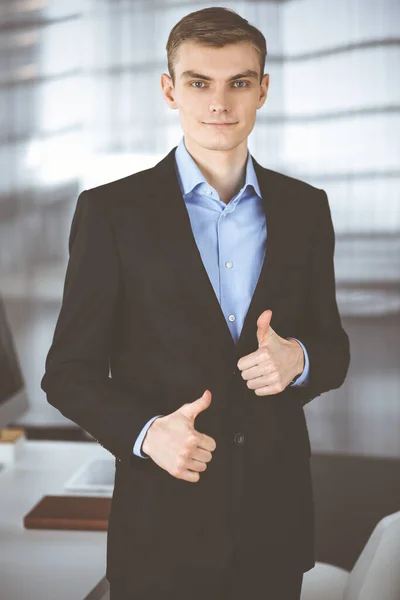 Joven hombre de negocios en un traje, mientras que de pie directamente en una oficina moderna.El éxito y el concepto de lugar de trabajo de negocios — Foto de Stock