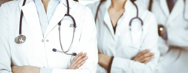Profesyonel doktorlardan oluşan bir grup klinikte kollarını kavuşturmuş bir takım olarak ayakta duruyor. Coronavirüs salgını sırasında ilaç kavramı — Stok fotoğraf