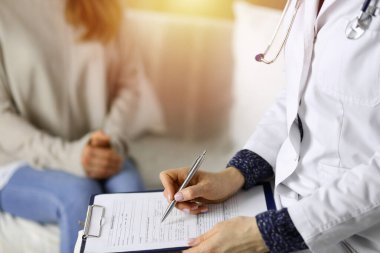 Kadın-doktor ve hasta yakın plan çekimleri. İçeride otururken sağlık muayenesini tartışıyorlar. Coronavirus salgını ve kendini izolasyon karantinası sırasında evde kal. Covid 2019
