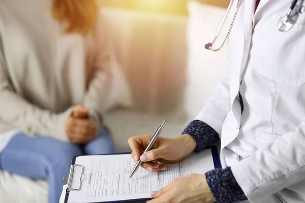 Kadın-doktor ve hasta yakın plan çekimleri. İçeride otururken sağlık muayenesini tartışıyorlar. Coronavirus salgını ve kendini izolasyon karantinası sırasında evde kal. Covid 2019