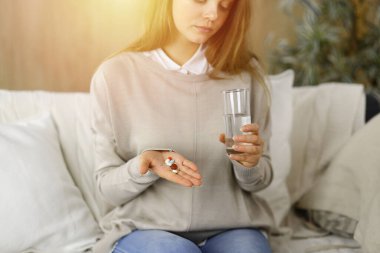 Yakın plan kadın hapları tutuyor, ilaç alıyor, baş ağrısını tedavi ediyor. Kişisel izolasyon ve Coronavirüs salgını sırasında tıp konsepti