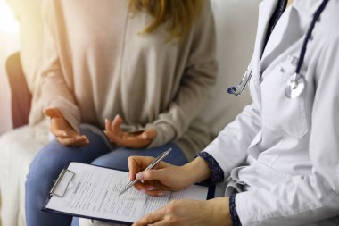 Kadın-doktor ve hasta yakın plan çekimleri. İçeride otururken sağlık muayenesini tartışıyorlar. Coronavirus salgını ve kendini izolasyon karantinası sırasında evde kal. Covid 2019