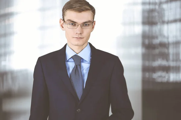 Jovem empresário vestindo terno, com óculos, enquanto estava no escritório. Conceito de sucesso empresarial hoje em dia — Fotografia de Stock