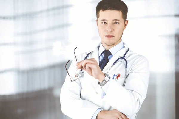 Dottore uomo, con occhiali e stetoscopio, è in piedi presso il suo ufficio in ospedale. Servizio medico perfetto in clinica. Buon futuro in medicina e sanità — Foto Stock