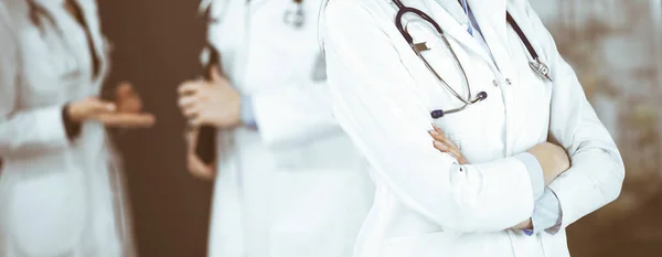 Una joven médica desconocida está de pie con los brazos cruzados en la clínica. Concepto de medicina durante la pandemia del Coronavirus — Foto de Stock