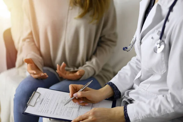 Kadın-doktor ve hasta yakın plan çekimleri. İçeride otururken sağlık muayenesini tartışıyorlar. Coronavirus salgını ve kendini izolasyon karantinası sırasında evde kal. Covid 2019