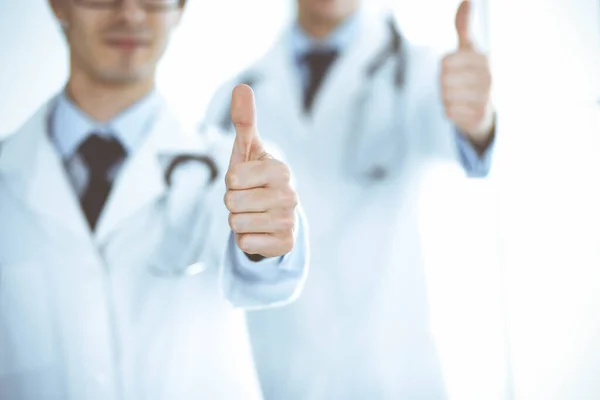 한 팀으로 서 있는 두 명의 남성 의사들 이 병원내 환자들을 위한 최고의 서비스의 상징으로 엄지손가락을 보여 주고 있습니다. 의학 과 건강 관리 — 스톡 사진