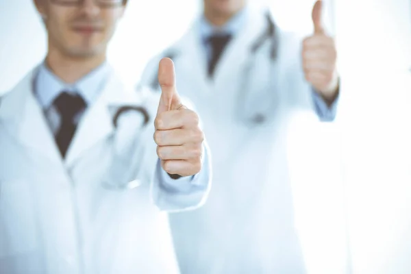 Twee mannelijke artsen staan als een team en tonen duimen omhoog als een symbool van de beste service voor patiënten in de kliniek. Geneeskunde en gezondheidszorg — Stockfoto