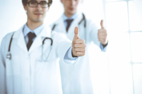 Twee mannelijke artsen staan als een team en tonen duimen omhoog als een symbool van de beste service voor patiënten in de kliniek. Geneeskunde en gezondheidszorg — Stockfoto