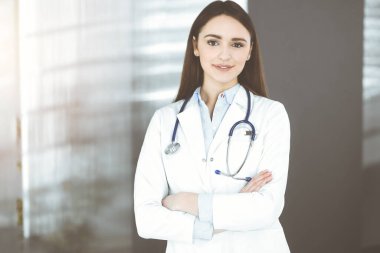 Gülümseyen genç bayan doktor kapalı bir klinikte duruyor.