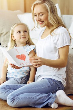 Güneşli dairede anneler günün kutlu olsun. Çocuk kızı annesini tebrik ediyor ve ona kalp çizimiyle kartpostal atıyor. Aile kavramı