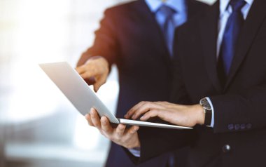 İş adamları, güneşli ve modern bir ofiste toplantının sunumunu tartışıyor. Meslektaşı ile birlikte bilinmeyen işadamı laptopta bazı bilgiler arıyor, avukatlar görüşmede.