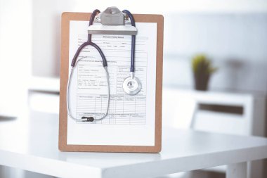 Üzerinde ilaç geçmişi olan steteskop ve dosya güneşli doktorların çalıştığı yerde masada. Tıp konsepti