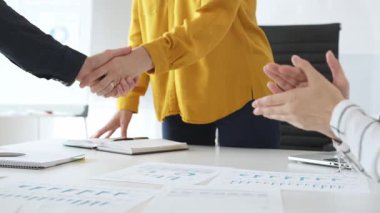 Profesyonel iş adamları el sıkışıyor, çağdaş ofis çalışma alanındaki toplantı masasının başında dururken ortaklık anlaşmasını onaylıyorlar. İş tokalaşması.