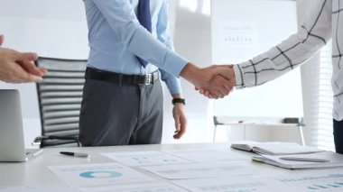 İş ortakları ofiste finansal tablolar, dizüstü bilgisayarlar ve raporlarla el sıkışıyor, başarıyı simgeliyor, takım çalışması, anlaşma, işbirliği ve kurumsal büyümeyi simgeliyor. İş adamlarının el sıkışması.