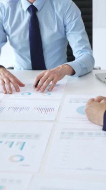 Gözlüklü güvenilir işadamı bir şirket toplantısına liderlik ediyor, mali tabloları gözden geçiriyor, veri içgörülerini açıklıyor ve iş arkadaşlarıyla stratejik büyüme fırsatlarını tartışıyor.