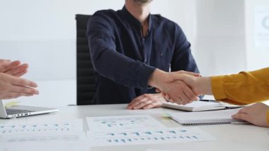 İş ortakları başarılı bir toplantının ardından el sıkışır, şık ve modern bir ofis ortamında iş anlaşmasını sağlamlaştırır. El sıkışma kavramı.