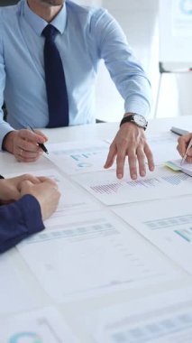 Gözlüklü güvenilir işadamı bir şirket toplantısına liderlik ediyor, mali tabloları gözden geçiriyor, veri içgörülerini açıklıyor ve iş arkadaşlarıyla stratejik büyüme fırsatlarını tartışıyor.