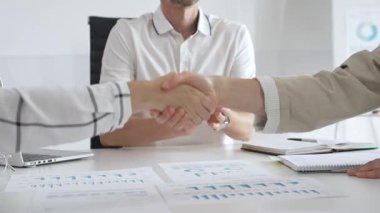 İş adamları iş yeri belgelerinin üzerinden el sıkışıyor, işbirliği ruhunu sembolize ediyor ve işyerindeki başarıyı paylaşıyorlar. El sıkışma kavramı.