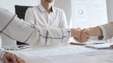 Çağdaş, güneşli bir ofiste otururken iki iş kadını el sıkışıyor, ortaklık anlaşmasını onaylıyor. İş tokalaşma kavramı.