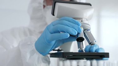 Laboratuvar araştırması sırasında mavi koruyucu eldiven takan bilim araştırmacısı ince ayar mikroskobu lensleri takıyor. Tıp, sağlık ve bilim konsepti.