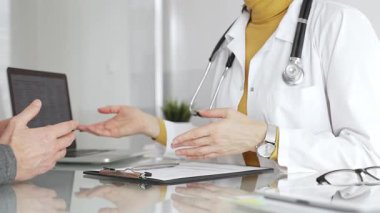 Doktor tıbbi bir randevu sırasında panoya notlar yazıyor, modern bir hastane ofisinde bir hastayla sağlık hakkında konuşuyor. Tıp, sağlık ve bilim konsepti