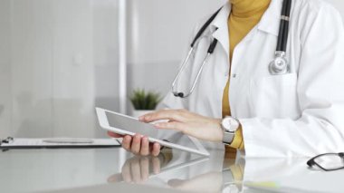 Klinikte dijital tablet kullanan laboratuvar önlüğü ve steteskop giyen bir doktor. Modern tıp ve tele sağlık konsepti. Tıp, sağlık ve bilim konsepti