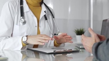 Doktor tıbbi bir randevu sırasında panoya notlar yazıyor, modern bir hastane ofisinde bir hastayla sağlık hakkında konuşuyor. Tıp, sağlık ve bilim konsepti