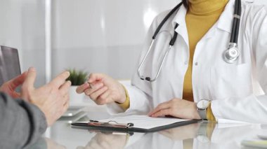 Doktor tıbbi bir randevu sırasında panoya notlar yazıyor, modern bir hastane ofisinde bir hastayla sağlık hakkında konuşuyor. Tıp, sağlık ve bilim konsepti