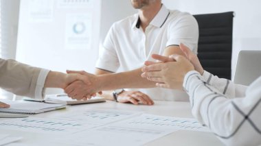 İş adamı, iş yeri belgeleri üzerinde kadın partnerle tokalaşıyor, işbirlikçi ruhu simgeliyor ve işyerindeki başarıyı paylaşıyor. İş tokalaşma kavramı.