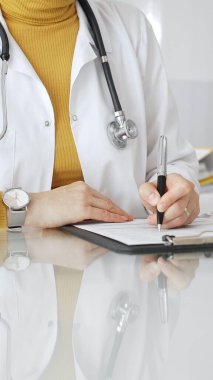 Doktor reçete ya da tıbbi kayıt tutuyor, modern klinikte profesyonel sağlık hizmetleri sağlıyor, not panosu ve dizüstü bilgisayarla. Tıp, sağlık ve bilim konsepti