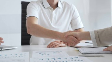 İş adamı, iş yeri belgeleri üzerinde kadın partnerle tokalaşıyor, işbirlikçi ruhu simgeliyor ve işyerindeki başarıyı paylaşıyor. İş tokalaşma kavramı.