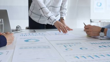 Kurumsal bir toplantıda tablo ve grafiklerle mali raporları tartışan bir grup profesyonel, takım çalışmasını, planlamasını, veri analizini ve stratejisini vurguladı