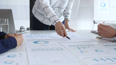 Kurumsal bir toplantıda tablo ve grafiklerle mali raporları tartışan bir grup profesyonel, takım çalışmasını, planlamasını, veri analizini ve stratejisini vurguladı