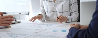 Bir iş toplantısı sırasında finansal belge ve çizelgeleri analiz eden bir grup profesyonel. Takım üyeleri veri analizi, strateji planlaması ve kurumsal büyüme hedeflerinde işbirliği yaparlar.