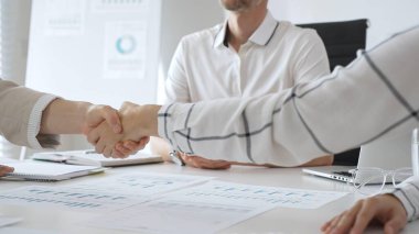 Çağdaş, güneşli bir ofiste otururken iki iş kadını el sıkışıyor, ortaklık anlaşmasını onaylıyor. İş tokalaşma kavramı.