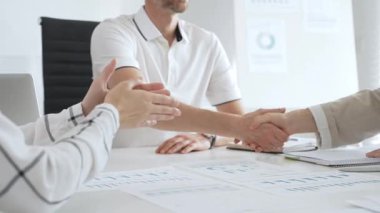 İş adamı, iş yeri belgeleri üzerinde kadın partnerle tokalaşıyor, işbirlikçi ruhu simgeliyor ve işyerindeki başarıyı paylaşıyor. İş tokalaşma kavramı.