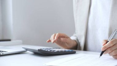 Yıllık vergisini hesaplayan profesyonel muhasebeci, mali belgeleri gözden geçiren, iş yerindeki bütçe detaylarını hesap makinesi ve evrak işleriyle takip eden. Ticarette denetim ve vergiler