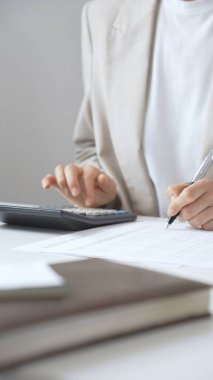 Yıllık vergisini hesaplayan profesyonel muhasebeci, mali belgeleri gözden geçiren, iş yerindeki bütçe detaylarını hesap makinesi ve evrak işleriyle takip eden. Ticarette denetim ve vergiler