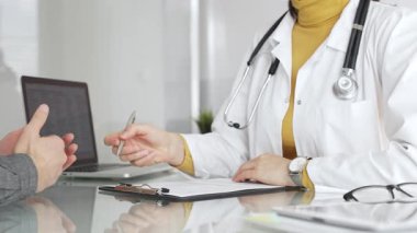 Doktor tıbbi bir randevu sırasında panoya notlar yazıyor, modern bir hastane ofisinde bir hastayla sağlık hakkında konuşuyor. Tıp, sağlık ve bilim konsepti